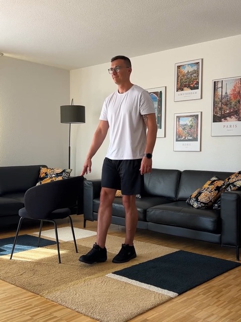 Christian Joschko übt im Wohnzimmer neben einem Stuhl als Halt